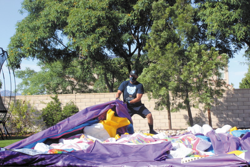 Alberto Frias sets up a bounce house, taking full safety precautions.